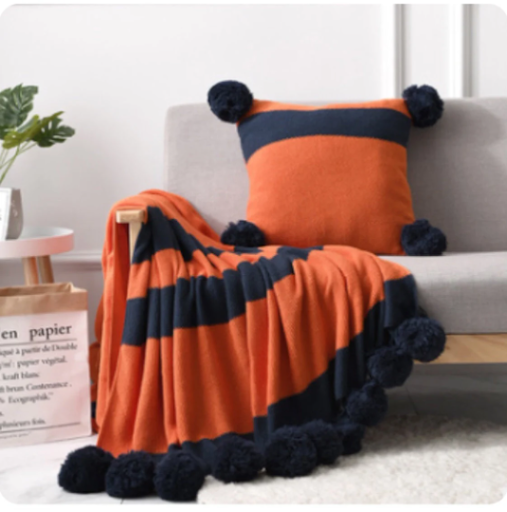 Luxury designer style Pom Pom throw blanket knitted orange and navy striped would enhance any interior